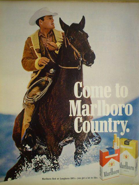 Roy N. Sickner as the Marlboro Man, on horseback in the snow in a fleece-lined jacket and white cowboy hat, beside the tagline 'Come to Marlboro Country' — Philip Morris Marlboro magazine campaign, late 1960s.